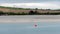 View of Clonakilty Bay at low tide. A small orange buoy is kept on a calm water surface. The shore