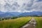 View of the cloudy mountains. A dirt road, meadows