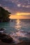 View of coastline on Nosy Komba Island lined with palm trees and boats floating in the sea at sunset, Nosy Komba