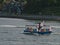 View of colorful little Aquabus boat, offering ferry connections in False Creek bay, Vancouver downtown with people passing by.