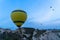 View of colorful yellow balloon and balloons flying over Cappadocia unique mountain landscape ground in morning light