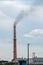 View of a complex of industrial buildings with smoking chimneys in the afternoon against the sky with clouds