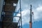 View of the construction site, scaffolding installed around the old building. The boom of the tower crane hangs over the temple