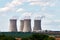 View of cooling chimneys of nuclear power plant. Landscape with forest and trees, green lawn under blue sky with clouds