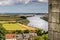 A view of cottage roofs, river, and farm fields.