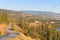 View of country road through forested hills with orchards, vineyards, and mountains in distance