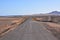 View of a countryside desert dirt road on a clear sky ba
