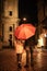 View of couple in autumn outfit walking under umbrella along evening street