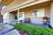 View of cozy porch with concrete walkway and trimmed hedges.