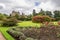 A view of Crathes Castle from a garden with a green lawn and several flower beds.