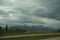 View of crooked highway passing through scenic snow-capped mountains under foggy sky in Canada