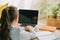 View of cute schoolchild using laptop while sitting at desk with copy books