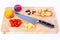 View of a cutting wooden board, an apple, a peach, tomatoes, pieces of pineapple, chicken, raisins and peanuts with a knife