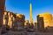 View of damaged obelisk of Hatshepdut in the middle of ancient ruins Hypostyle Hall and statue of pharaoh