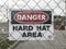 View of a Danger - Hard Hat Area sign on a chain link fence outside a construction zone