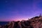 View at dawn of purple sky with stars and rocky pier in mallorca. dramatic and relaxing view of sunset in porto colom port with