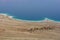 View on Dead sea shoreline, bright blue water and light brown layers of sand. Area of desert next to the beach