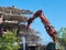 View on deconstruction works by heavy pneumatic crane excavator with special equipment. Buildings and houses Industrial destroyer