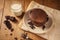 A view of delicious cocoa pancakes with dark chocolate and powdered sugar on a wooden table