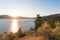 View of desert grasses and sagebrush with lake and sun setting behind mountains