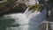 View of a detail of a small waterfall among rocks in the mountains. Water flowing with splashes through wet rocks and stones