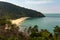 A view of a distant beach surrounded by lush forest on the island of Koh Lanta, Thailand, the beach looks totally empty and