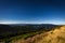 View from Dlouhe strane top reservoir to valley with wind turbine and green forest, dark blue sky