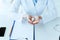 View of doctor with handful of pills sitting at workplace near clipboard