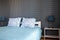 View of the double bed with a blue bedspread and white pillows against a dark wall and nightstands with lamps. Home, vacation conc