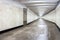 A view down a damp tiled block and concrete tunnel urban or city pedestrian underpass corridor with white wall and