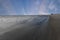 View down a deserted long wet beach with many small birds feeding on the wet sand. There is a dramatic sky