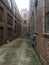 View down a long alley between brick industrial buildings