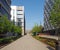 a view down a long pedestrian street between leeds university and a car park building lines with trees and flowerbeds with a