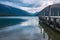 A view down the side of a wooden jetty of the incredibly beautiful Rotoiti Lake surrounded by mountains.