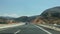 View of driver car window looking at cars on Highway with view on mountain peaks