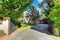 View of driveway with opened gate. Double garage and well kept garde