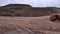 View of driving dump truck on sandy soil. Scene. Orange dump truck rides on quarry with ground in lowlands