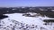 The view from the drone. Clip.Winter forests where small houses of the village are visible and large snowdrifts and blue