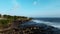 A view from a drone flying over the sea with waves and shore views with clouds above and rocks below