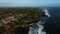 A view from a drone flying over the sea with waves and shore views with clouds above and rocks below