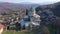 View from drone of restored ancient Gelati Monastery of Virgin on wooded hillside on sunny spring day. Religious and