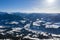 View from a drone on a winter mountains covered with forests and snow in Alps and small villages