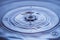 View of drops making circles on blue water surface isolated on background.