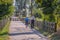 View of eco pedestrian / cycle lane, with couple of senior farmers, walking and carrying agricultural tools