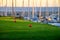 View on evergreen grass field on large golf course, green section with big red foam balls for beginners and yachts on Tenerife