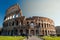 View of the exterior of the Colosseum in Rome with green lawn in front on a spring day