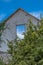 View of facade of ruined house, window with view of the sky, vegetation and some clouds in the sky