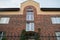 View on facade of two-story town house with decorative bricks, arched top, high windows and entrance with green wild grapes