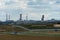 View of a factory with pipes next to an agricultural field. An oil refinery near the city against the background of clouds