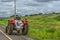 View of a farm tractor on roadside, natural grassland landscape with power lines as background